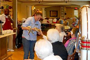 Educator Catherine shows a gopher snake to a group of older adults